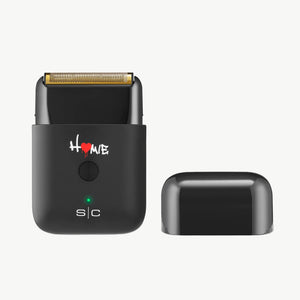 Homie Nano Single Foil Shaver
shown with its matching black lid cap on a plain white background. The device features a gold-colored metal cutting edge, a green LED indicator light, and the brand name 's|c' printed on the front.