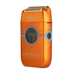 An orange metallic electric razor with blue accents and a gold-colored shaving head, shown on a plain white background. The brand name 'INSTINCT' is printed on the lower front, and 's|c' is visible near the top.