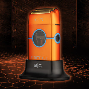 An orange and black S|C Instinct electric razor with blue accents, displayed on its black charging dock against a dark, futuristic background with glowing orange hexagonal patterns.