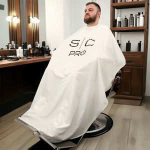 man sitting in barber chair with cutting cape