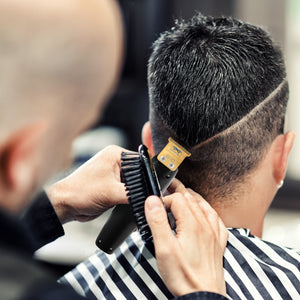 Barber cutting a customer's hair with Saber precision black trimmer in a salon setting