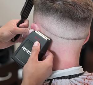 Person using Rebel Professional Double Foil Shaver on another person's head with a blurred background