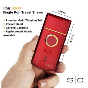A hand holding a red pocket-sized travel shaver with gold trim and a circular gold button. The image includes text describing the product as 'The UNO Single Foil Travel Shaver' with dimensions and feature bullet points, on a white background.