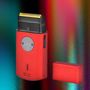 Uno 2.0 Professional Single Foil Shaver with a black and gold shaving head, shown next to its matching lid on a colorful, textured background.