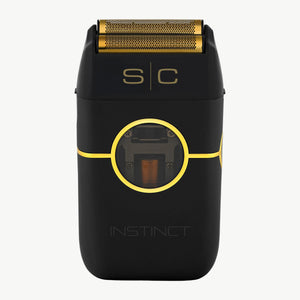 Instinct Metal Professional Double Foil Shaver, including a gold metallic shaving head, gold 's|c' branding, and a gold circular accent line on the front. The word 'INSTINCT' is printed in gold near the bottom.