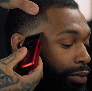A close-up of a man receiving a beard and side hair trim with the Uno 2.0 Professional Single Foil Shaver held by a tattooed hand.