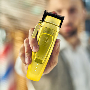 Gold metal Saber 2 digital brushless clipper held by man out of focus.