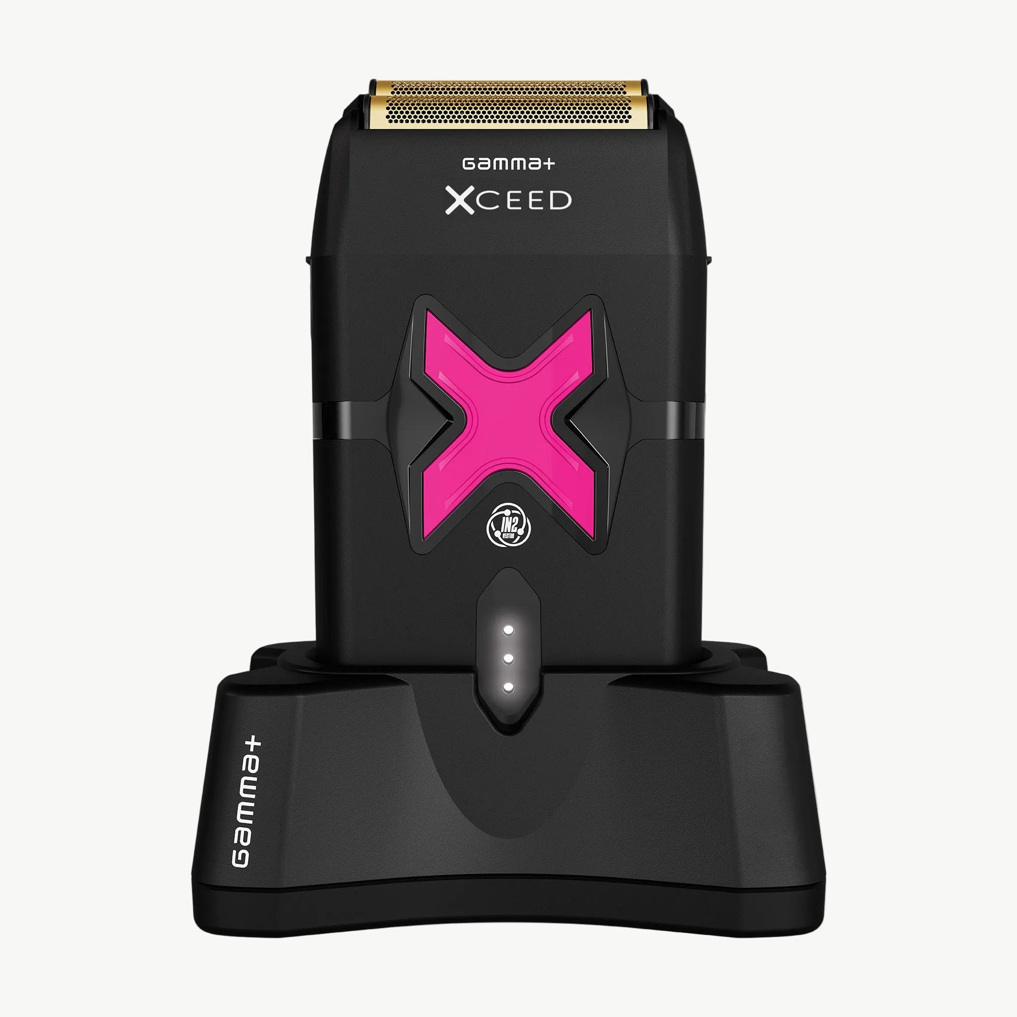 Xceed Gamma+ electric shaver with a metallic gold blade and a prominent pink 'X' accent, shown standing on its matching black charging dock against a white background.
