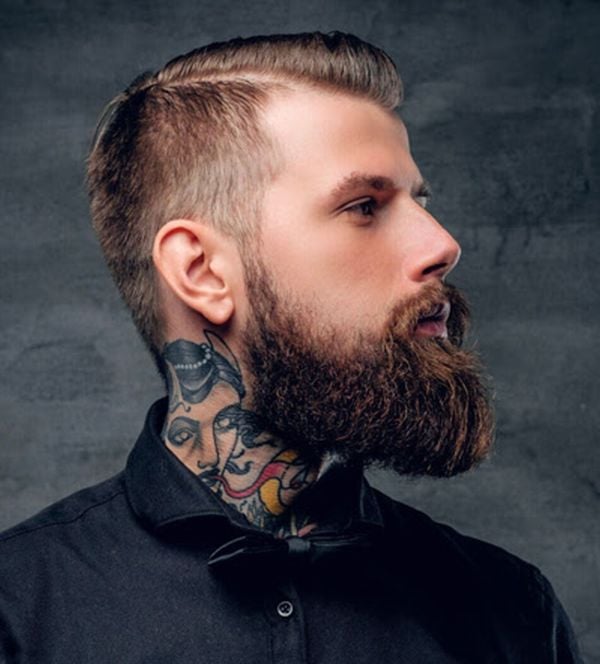 Image of a man with tattoos and a beard on a grey background